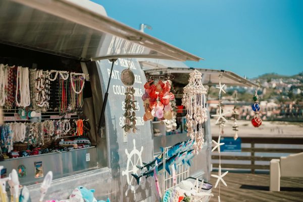 A vibrant display of beach souvenirs and accessories at a sunny seashore market stall.