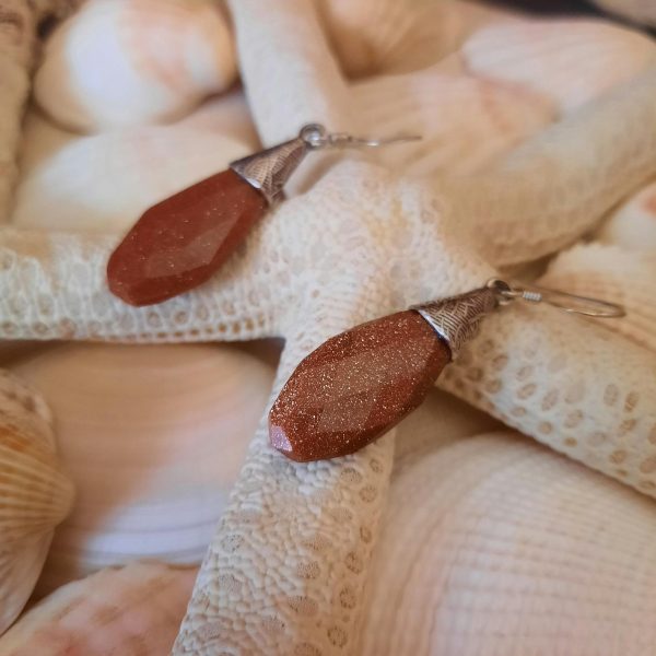 Elegant earrings displayed on seashells and starfish, perfect for beach lovers.